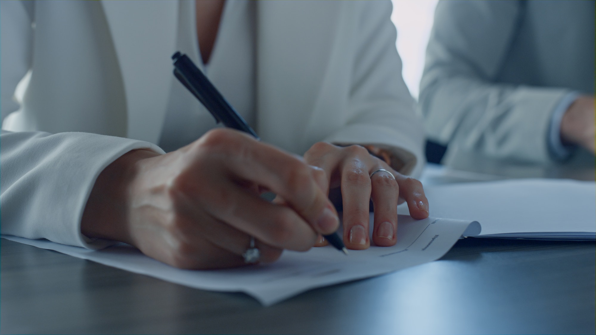 Closeup hand holding pen. Divorcing woman signing documents in attorney office.